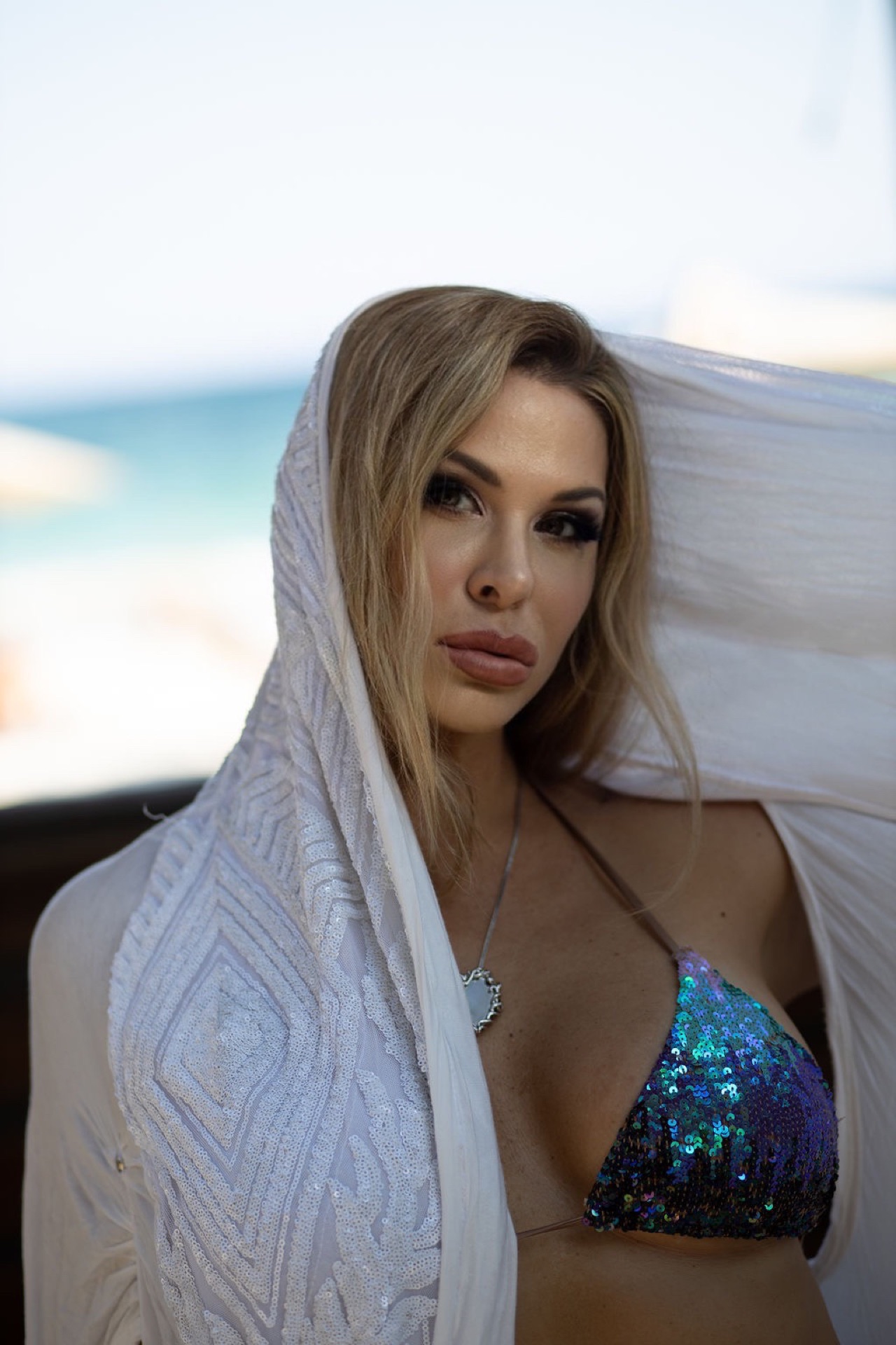 A woman wearing a white shawl beside the sea